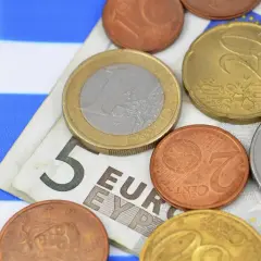 Euro to waluta w Grecji. Monety i banknot 5 euro na tle greckiej flagi.