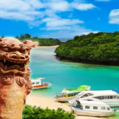 Kamienna lwica strzeże rajskiej plaży z łodziami na turkusowej wodzie. Archipelag z Okinawą w tle, z bujną zielenią i błękitnym niebem.