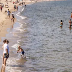 Ludzie na plaży i w wodzie. Widać falowanie, które może być związane z **upwellingiem**, czyli wynoszeniem zimnych wód głębinowych na powierzchnię.