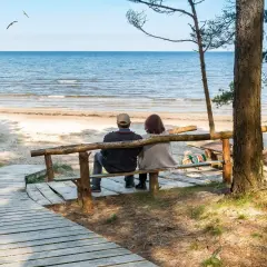 Para relaksująca para siedzi na ławce, patrząc na morze. Idealne miejsce na sanatoria nad morzem.