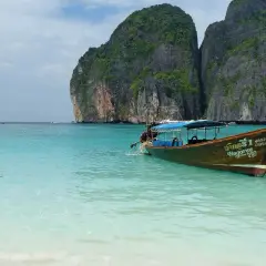 Łódź kołysze się na turkusowych wodach Maya Bay, otoczonej stromymi, porośniętymi zielenią klifami.