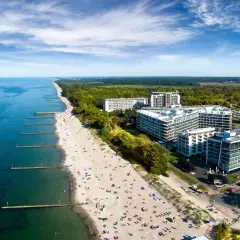 Nowoczesny hotel 5 gwiazdkowy nad morzem z widokiem na plażę pełną wypoczywających.