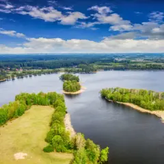 Malowniczy krajobraz z jeziorami i lasami. Widoczna polska wyspa porośnięta drzewami, otoczona wodą.