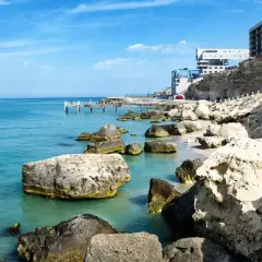 Brzeg Kaspijskiego Morza, największego jeziora na świecie, z kamienistą plażą, klifami i nowoczesnymi budynkami.