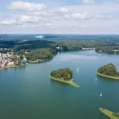 Malowniczy widok na jedno z najpiękniejszych jezior w Polsce, z wyspami, żaglówkami i miasteczkiem na brzegu.