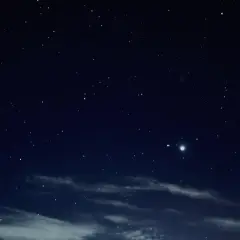Gwieździste niebo nocą, z widocznym jasnym obiektem, być może planetą, podczas nowiu księżyca.