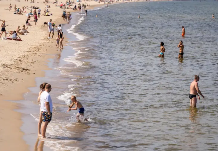 Ludzie na plaży i w wodzie. Widać falowanie, które może być związane z **upwellingiem**, czyli wynoszeniem zimnych wód głębinowych na powierzchnię.