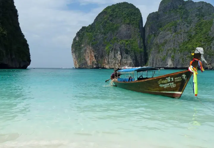 Łódź kołysze się na turkusowych wodach Maya Bay, otoczonej stromymi, porośniętymi zielenią klifami.