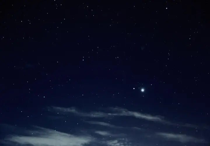 Gwieździste niebo nocą, z widocznym jasnym obiektem, być może planetą, podczas nowiu księżyca.