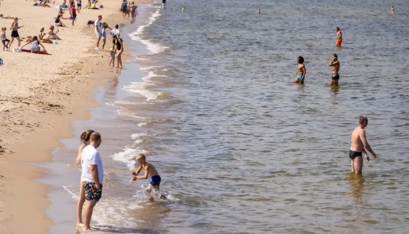 Ludzie na plaży i w wodzie. Widać falowanie, które może być związane z **upwellingiem**, czyli wynoszeniem zimnych wód głębinowych na powierzchnię.