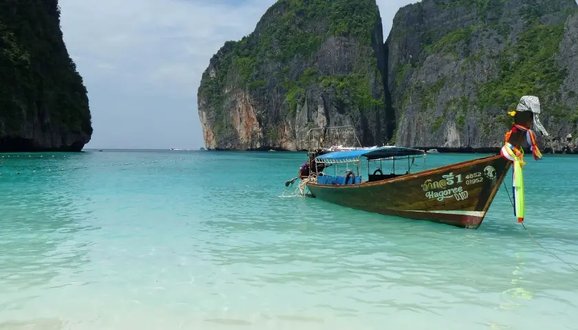 Łódź kołysze się na turkusowych wodach Maya Bay, otoczonej stromymi, porośniętymi zielenią klifami.