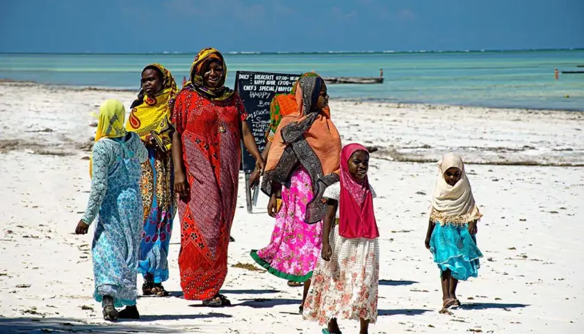 Kobiety w kolorowych strojach spacerują po plaży. Czy Zanzibar to państwo? Tak, to autonomiczny region Tanzanii.