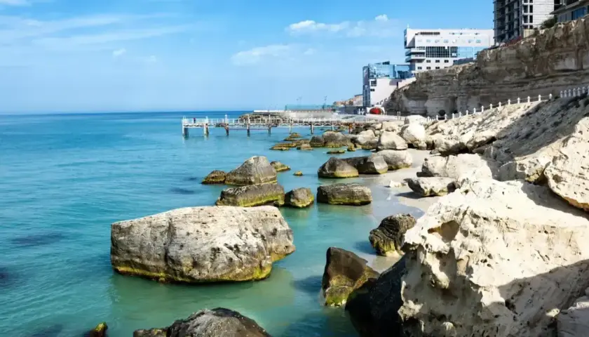 Brzeg Kaspijskiego Morza, największego jeziora na świecie, z kamienistą plażą, klifami i nowoczesnymi budynkami.