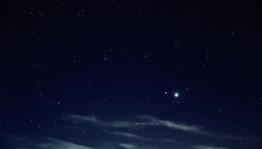 Gwieździste niebo nocą, z widocznym jasnym obiektem, być może planetą, podczas nowiu księżyca.