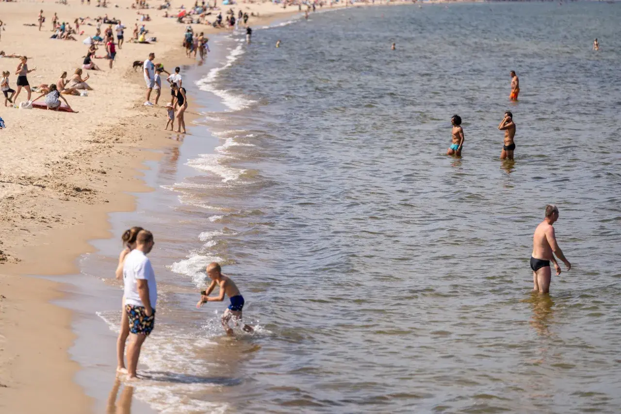 Ludzie na plaży i w wodzie. Widać falowanie, które może być związane z **upwellingiem**, czyli wynoszeniem zimnych wód głębinowych na powierzchnię.
