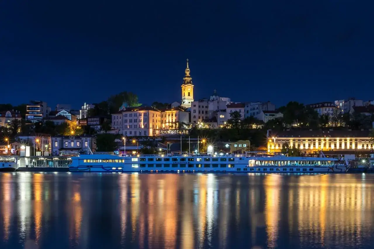 Nocny widok na Belgrad, stolicę Serbii, z rzeką i statkiem wycieczkowym.