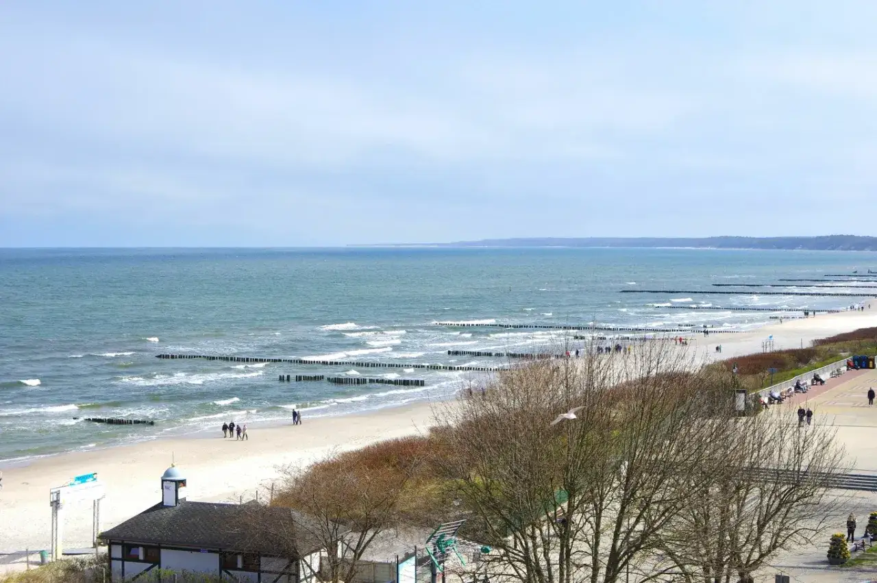 Spokojny dzień nad morzem, idealny na wypoczynek w sanatoriach nad morzem. Piękna plaża, fale i spacerujący ludzie.