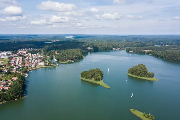 Malowniczy widok na jedno z najpiękniejszych jezior w Polsce, z wyspami, żaglówkami i miasteczkiem na brzegu.